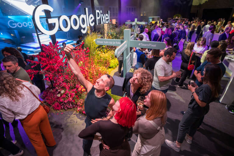 Deelnemers maken een selfie in een ruimte die is ontworpen in de kleuren van Google Pixel, tijdens een B2B-evenement