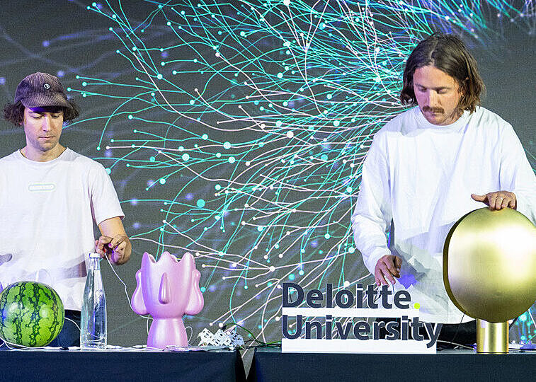 Artistic performance using original sound objects on stage, with a colorful neural-pattern backdrop.